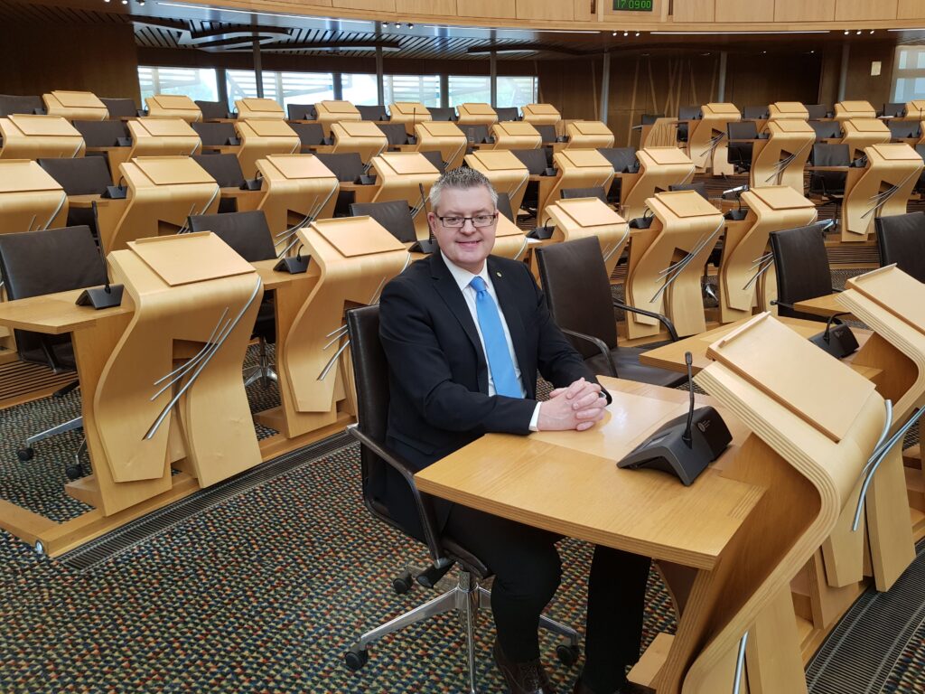Stuart at his desk in the main chamber of the Scottish Parliament.